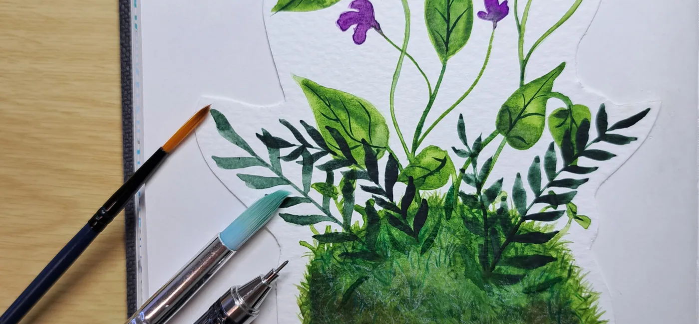 Gros plan kokedama illustré encre colorex, feuillages verts variés fleurs violettes, pinceaux et crayon posés à côté