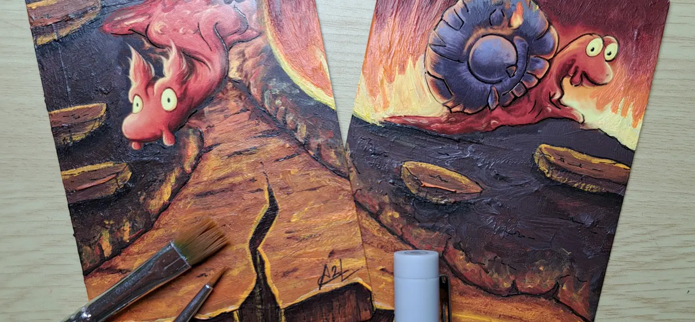Deux carte Pokemon customisée Limagma et Volcaropod côte à côte, peinture acrylique texturée tons rouges orangés, pinceau posé devant